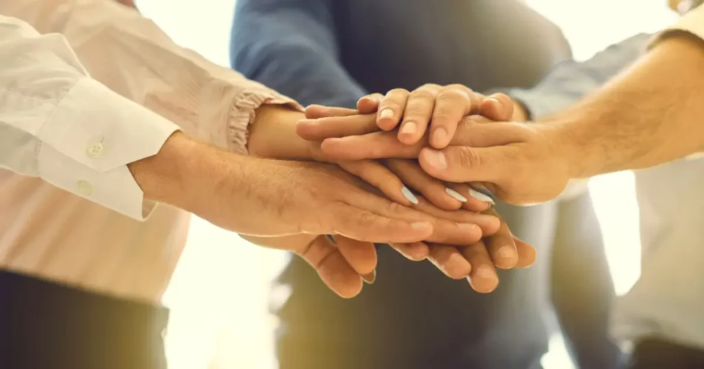 A group of people joining hands in the middle of a circle