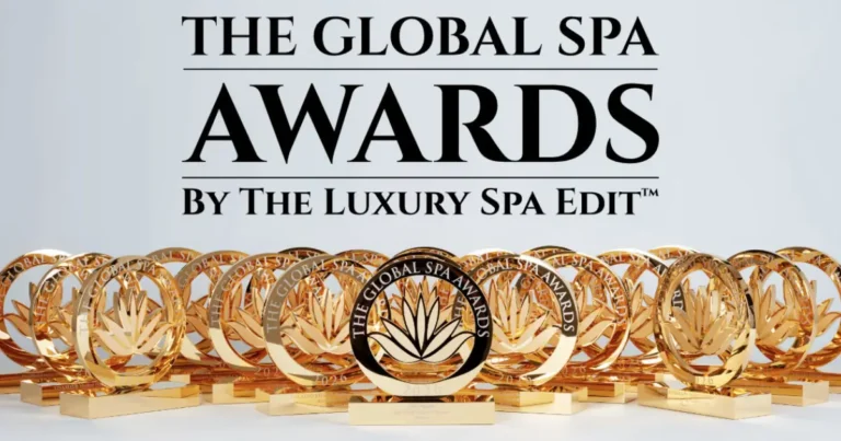 The words "THE GLOBAL SPA AWARDS BY THE LUXURY SPA EDIT™" in bold, black text positioned above a display of numerous shiny gold trophies. Each circular trophy features a central lotus flower motif and is engraved with the text "THE GLOBAL SPA AWARDS 2026"